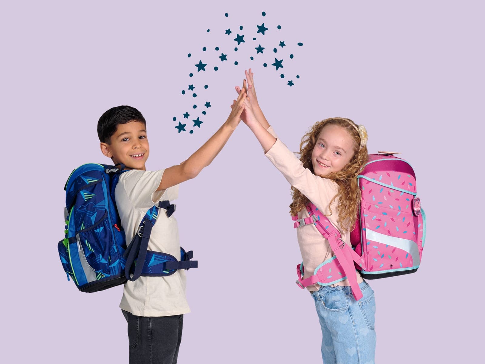 Zwei Kinder mit blauem und pinkem DerDieDas-Schulranzen geben sich ein High Five vor fliederfarbenem Hintergrund