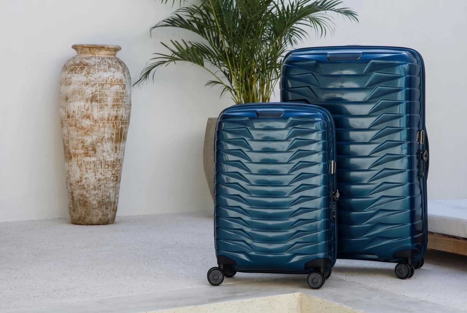 Zwei blaue Samsonite Koffer neben einer Pflanze und einer Vase